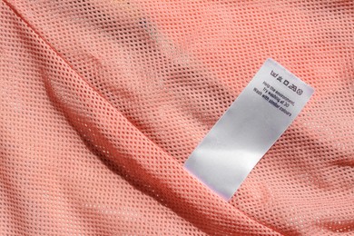 Photo of Clothing label with instruction on pink garment, closeup. Space for text