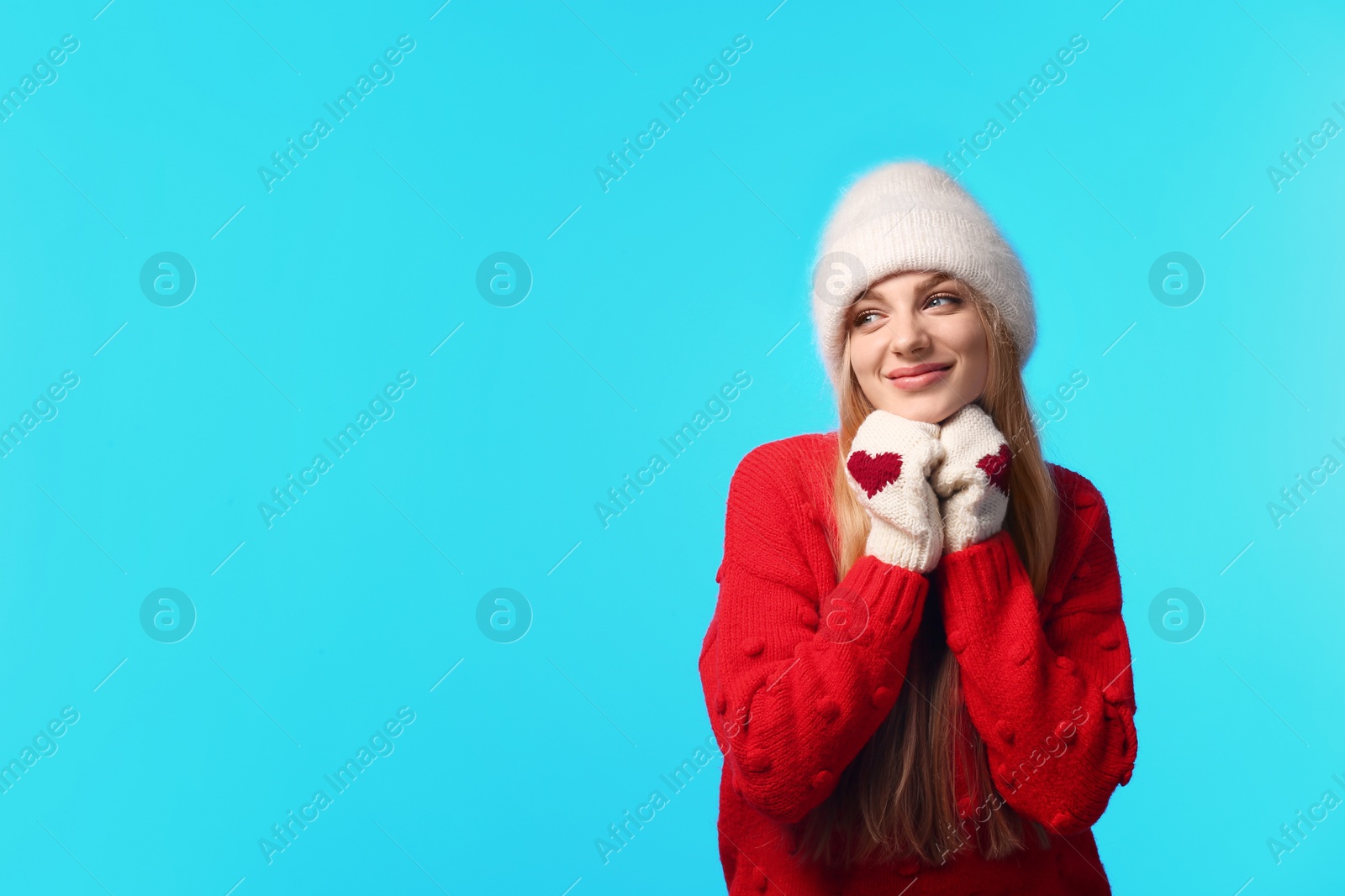 Photo of Portrait of emotional young woman in stylish hat, sweater and mittens on color background, space for text. Winter atmosphere