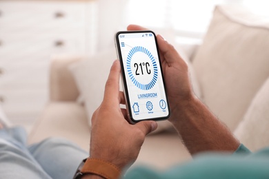 Man using smartphone to control heating system in house, closeup