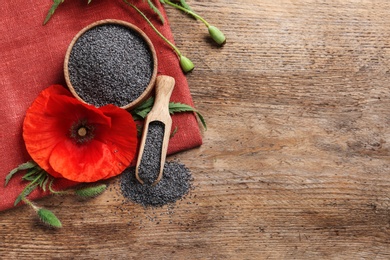 Flat lay composition with poppy seeds and flower on wooden table, space for text