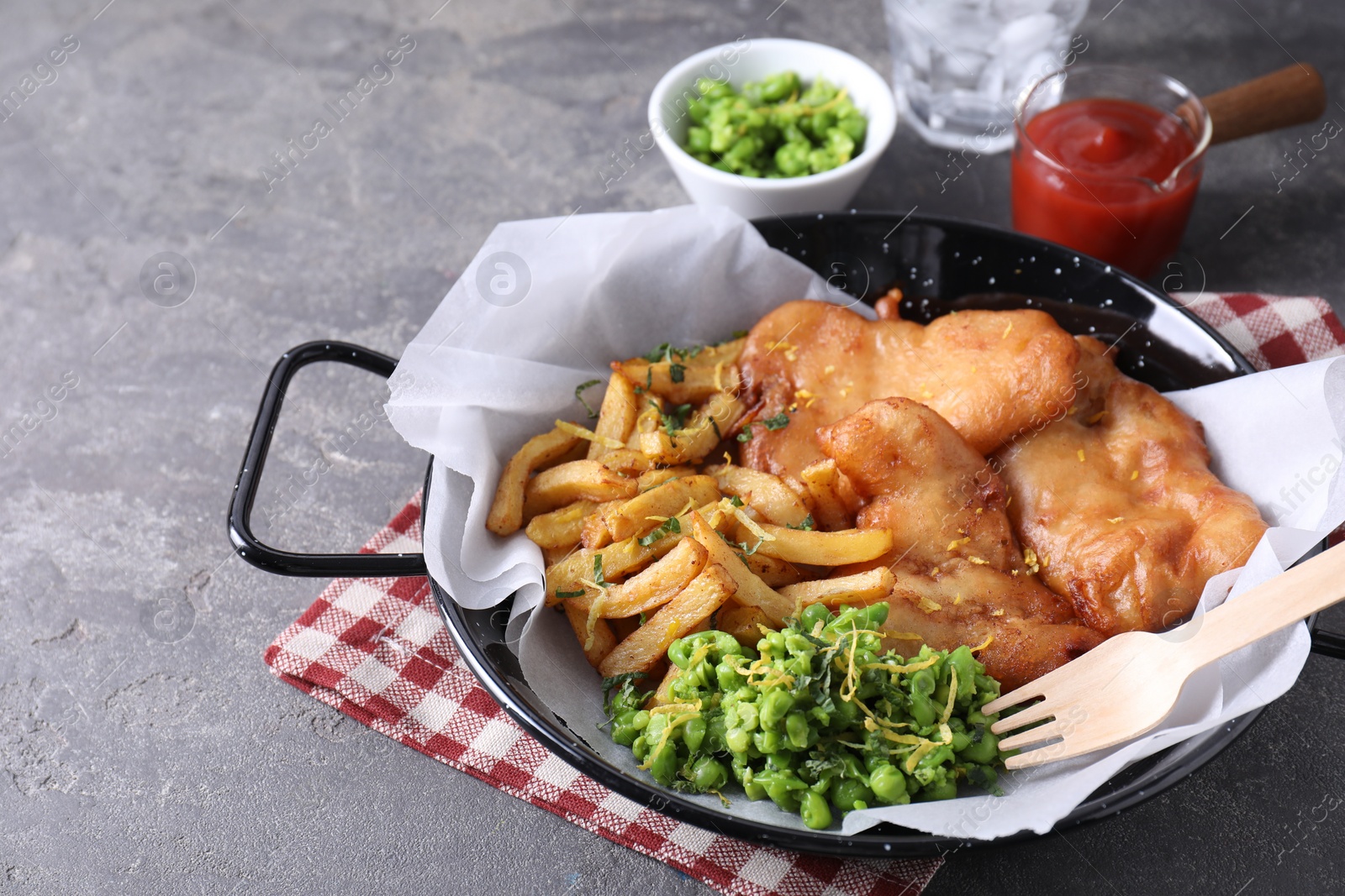 Photo of Tasty fish, chips, sauce and peas on grey table, closeup. Space for text