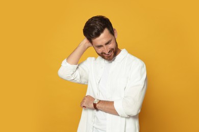 Photo of Portrait of smiling bearded man with wristwatch on orange background