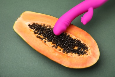 Half of papaya and purple vibrator on dark grey background, top view. Sex concept