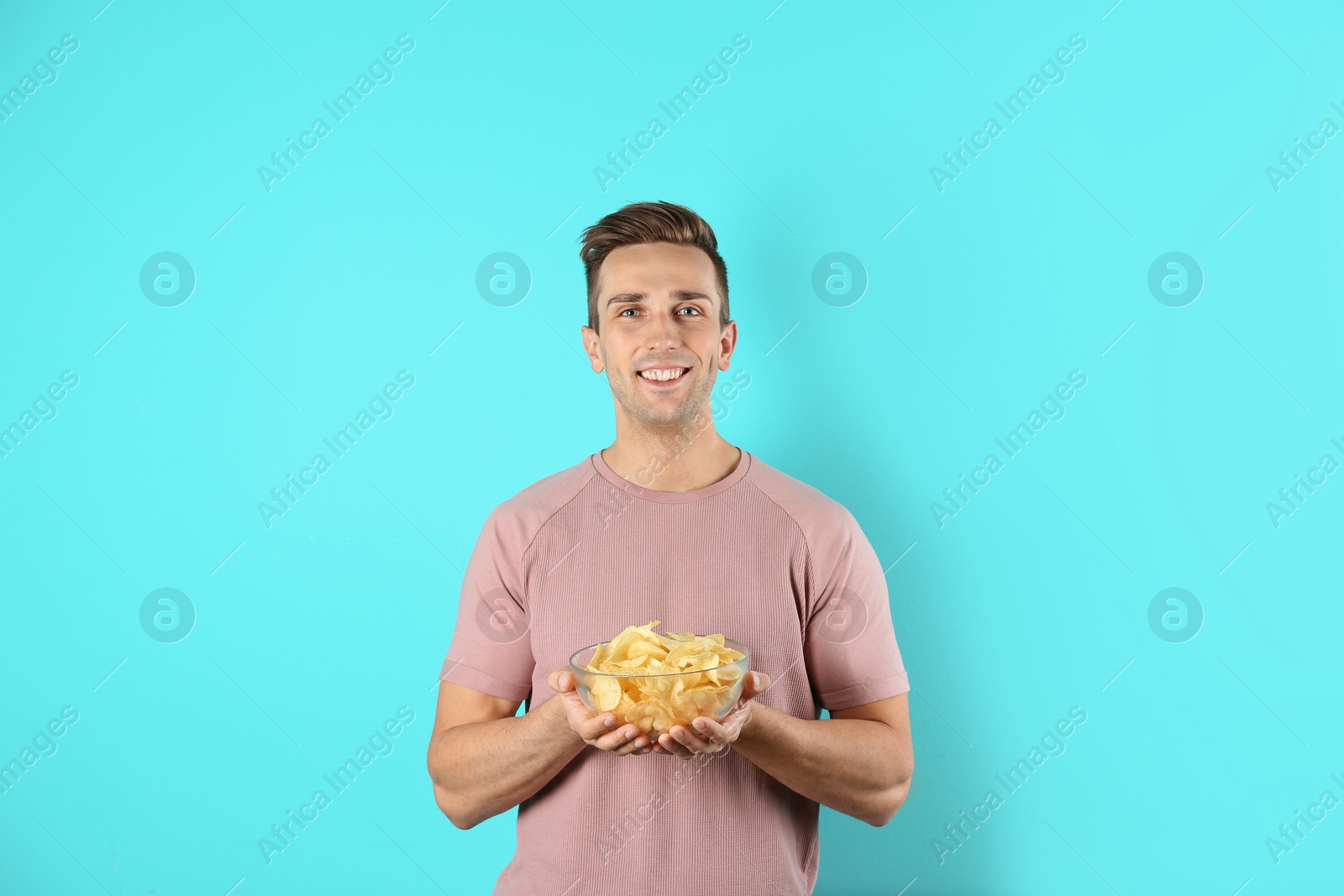 Photo of Man with bowl of potato chips on color background