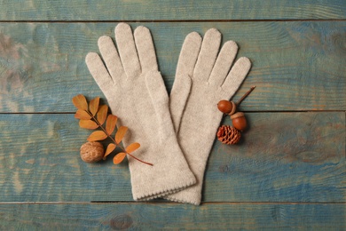 Photo of Stylish beige woolen gloves and autumn decor on blue wooden table, flat lay
