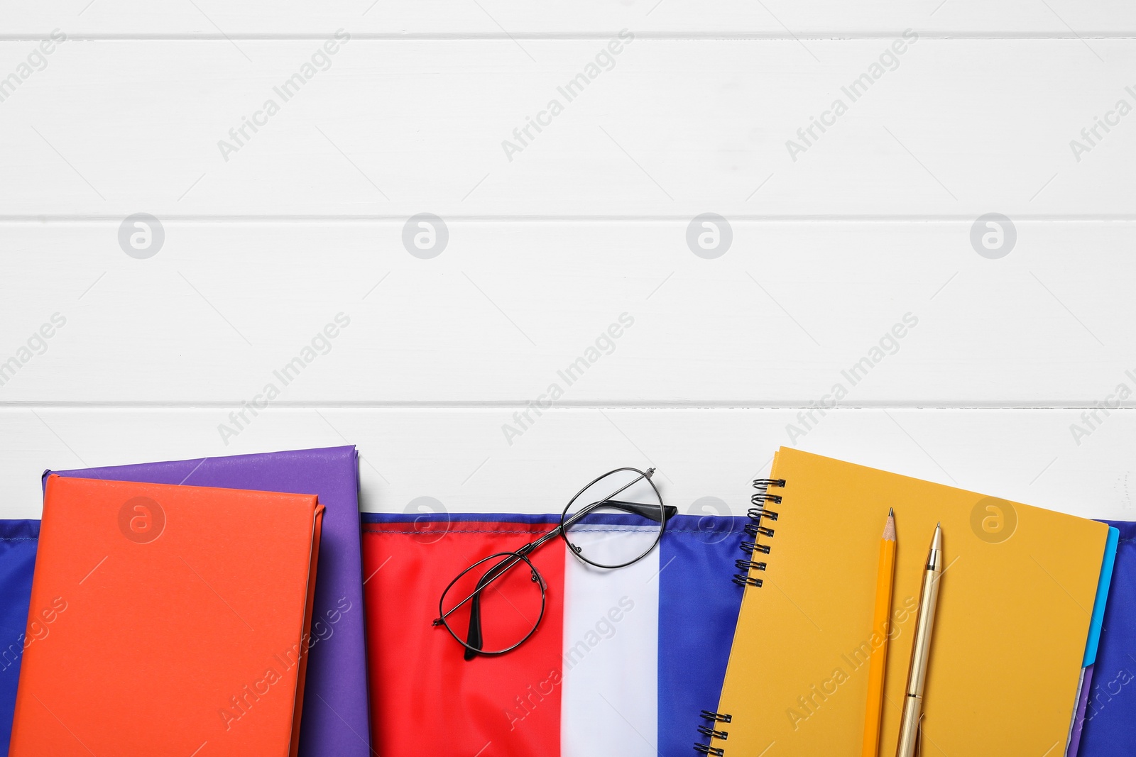 Photo of Learning foreign language. Flag of United Kingdom, books, stationary and glasses on white wooden table, flat lay with space for text