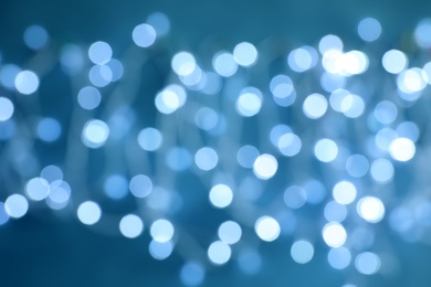 Blurred view of Christmas lights on color background