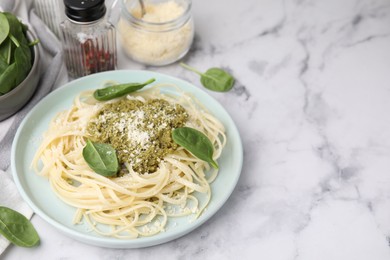 Photo of Tasty pasta with spinach, cheese and sauce on white marble table, space for text