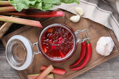 Photo of Tasty rhubarb sauce and ingredients on wooden table, flat lay