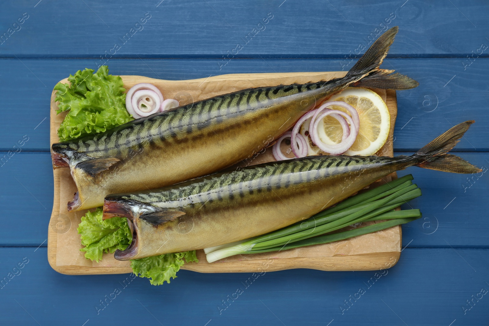 Photo of Delicious smoked mackerels and products on blue wooden table, top view
