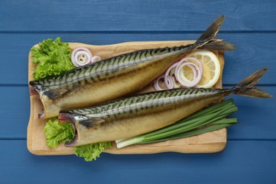 Photo of Delicious smoked mackerels and products on blue wooden table, top view