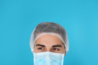 Photo of Young medical student with face mask and surgical cap on color background, closeup