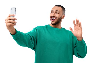 Photo of Smiling young man taking selfie with smartphone on white background