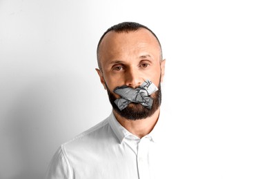 Mature man with taped mouth on white background. Speech censorship