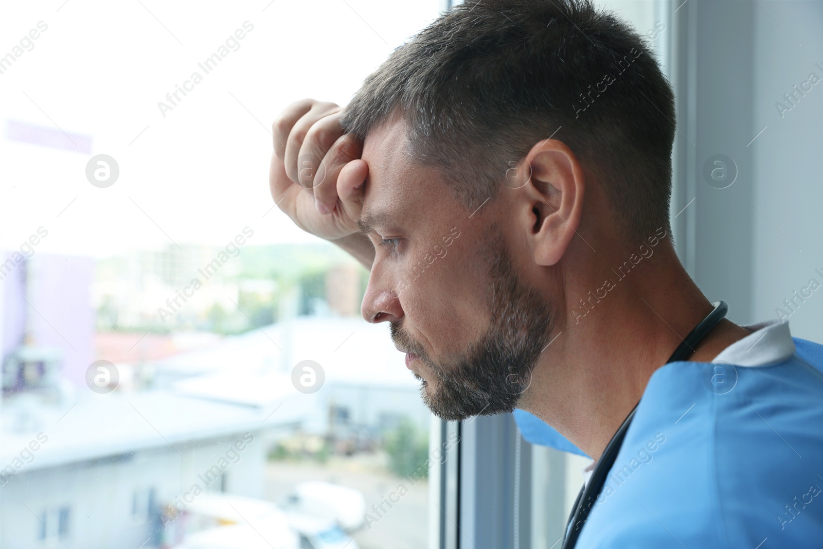 Photo of Exhausted doctor looking out of window in hospital