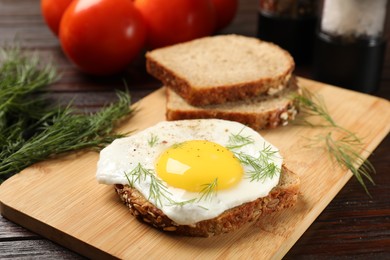 Photo of Tasty sandwich with fried egg on wooden table, closeup