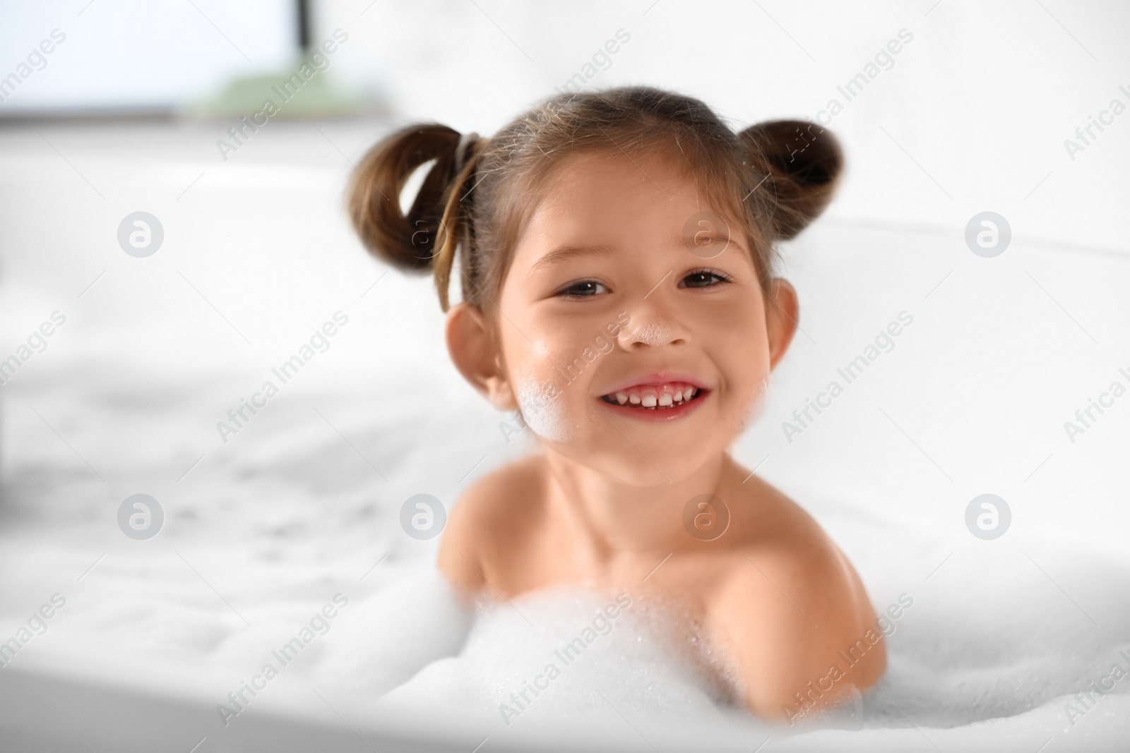 Photo of Cute little girl taking bubble bath at home