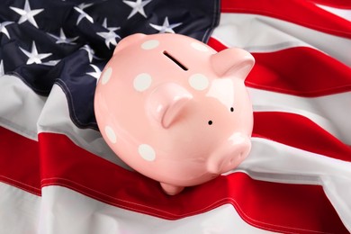 Photo of Pink piggy bank on American flag, closeup