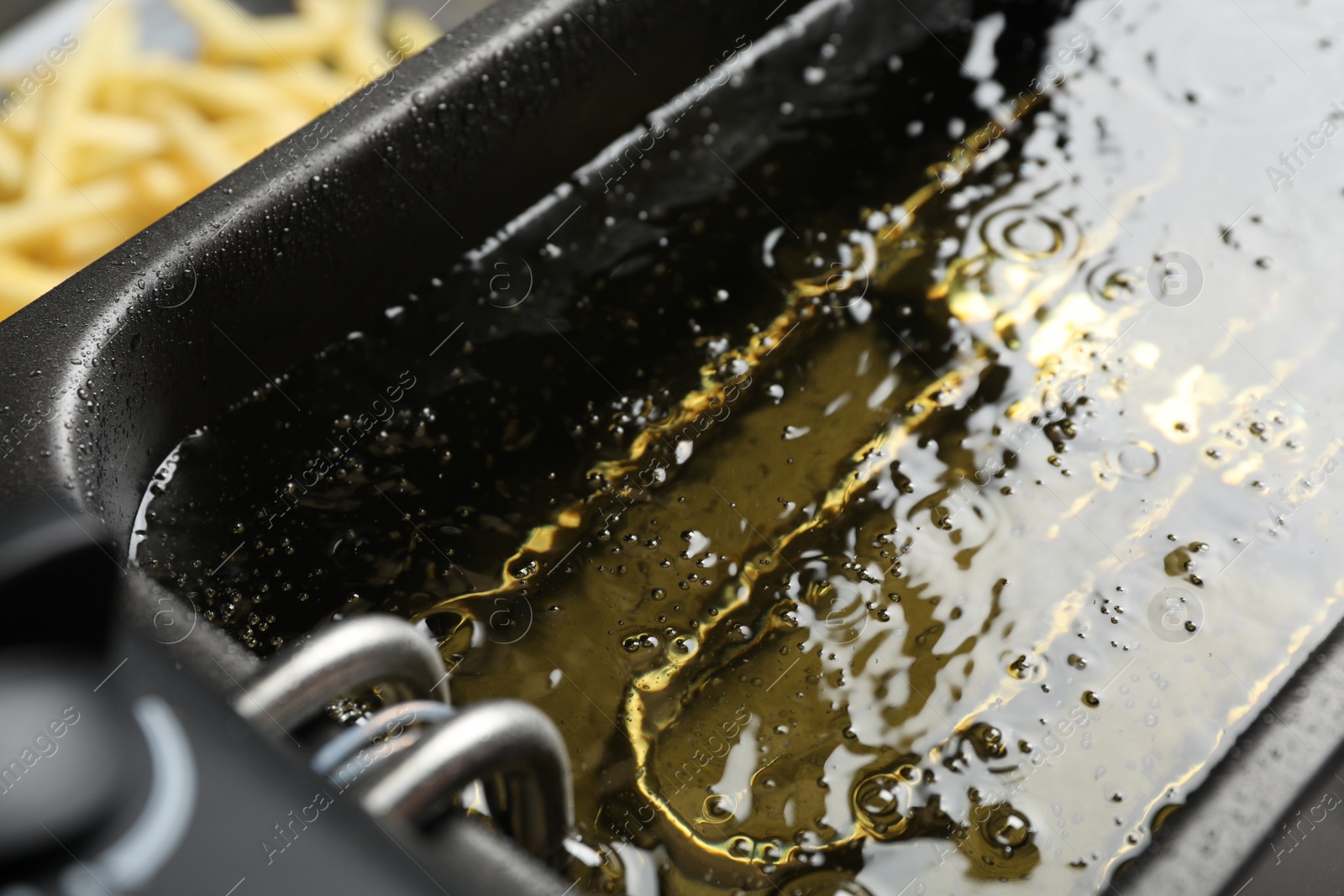 Photo of Hot cooking oil in deep fryer, closeup