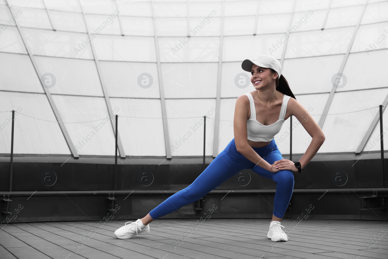 Photo of Beautiful woman in stylish sportswear stretching outdoors, space for text