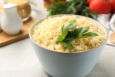 Delicious bulgur with parsley on light grey table, closeup