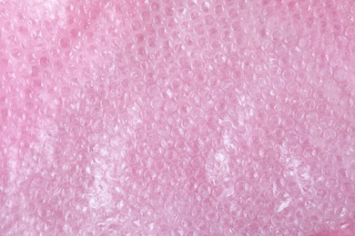 Photo of Transparent bubble wrap on pink background, top view