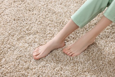 Photo of Woman on soft light brown carpet at home, closeup. Space for text