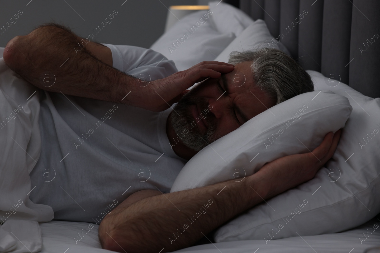 Photo of Mature man suffering from headache in bed at night