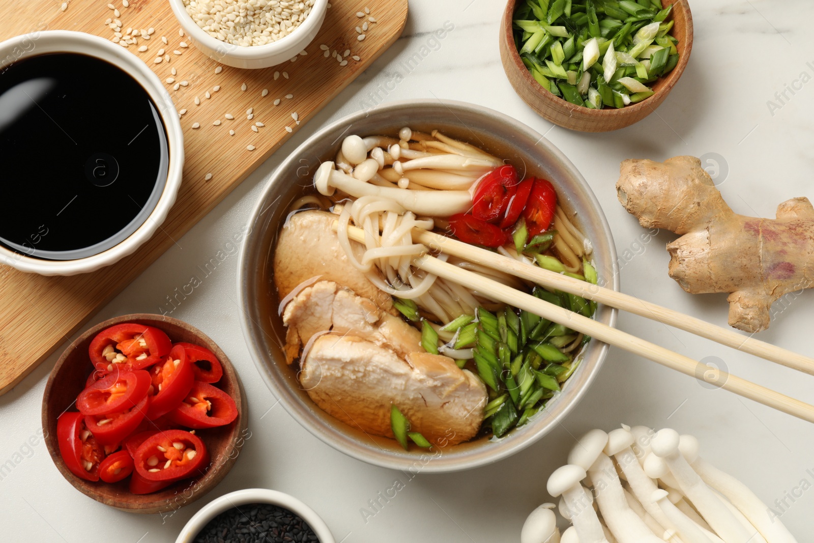 Photo of Delicious ramen with meat and ingredients on white marble table, flat lay. Noodle soup