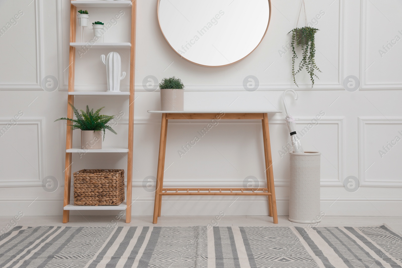 Photo of Console table with shelving unit and mirror on white wall in hallway. Interior design