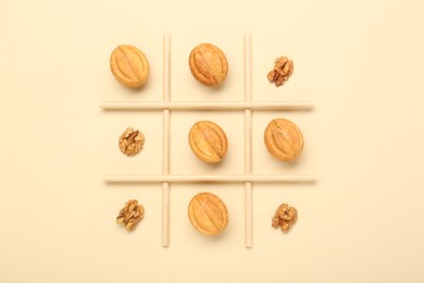 Photo of Tic tac toe game made with walnuts and cookies on beige background, top view