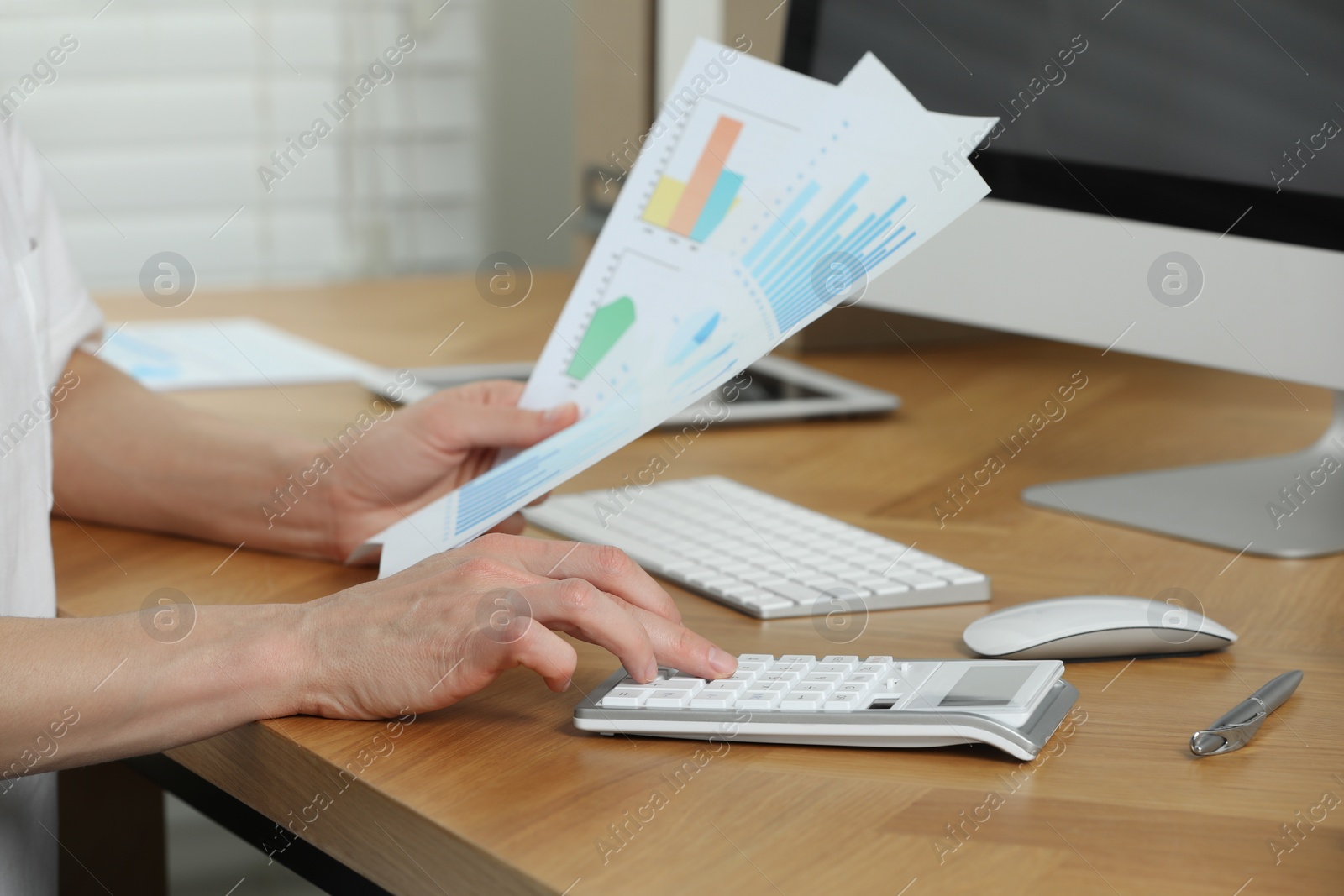 Photo of Professional accountant using calculator at wooden desk in office, closeup