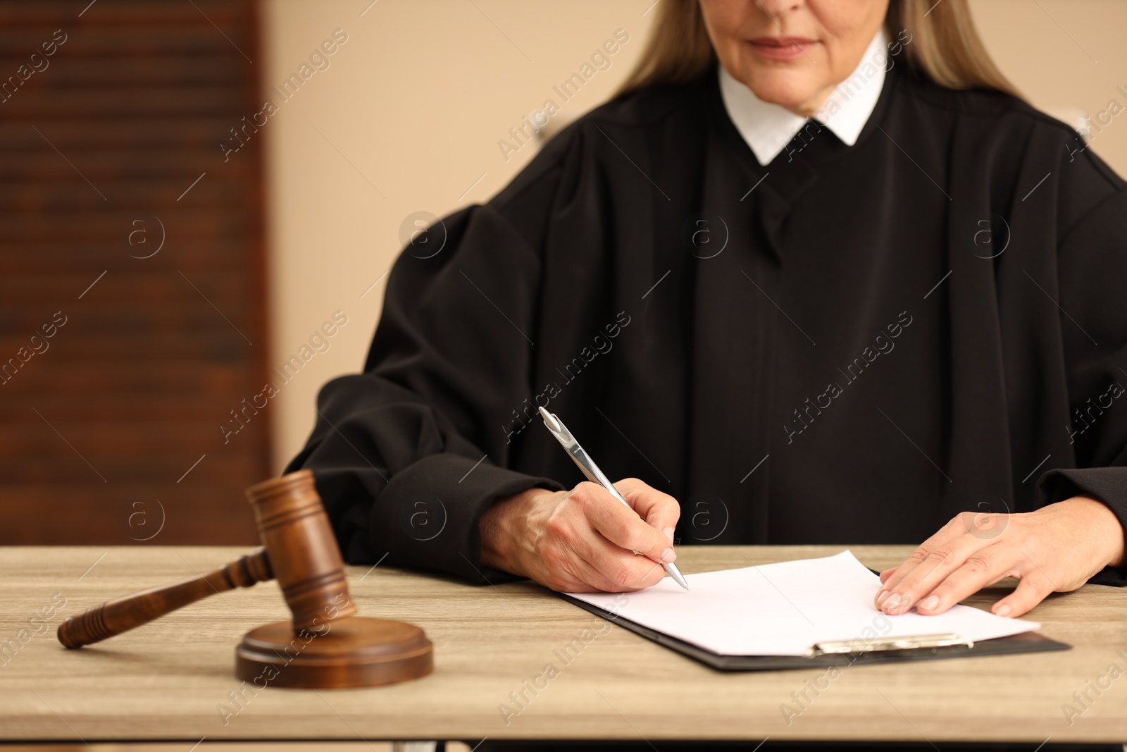 Photo of Judge working with document at table indoors, closeup