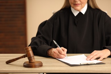 Photo of Judge working with document at table indoors, closeup