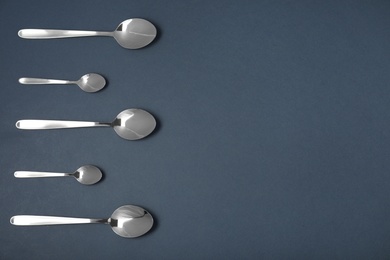 Photo of Set of different spoons on black background, flat lay with space for text