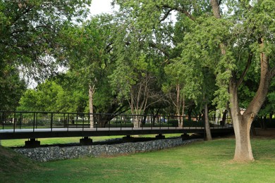 Picturesque view of bridge with metal railing and many trees in park