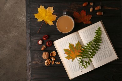 Flat lay composition of book with leaves as bookmark on wooden table