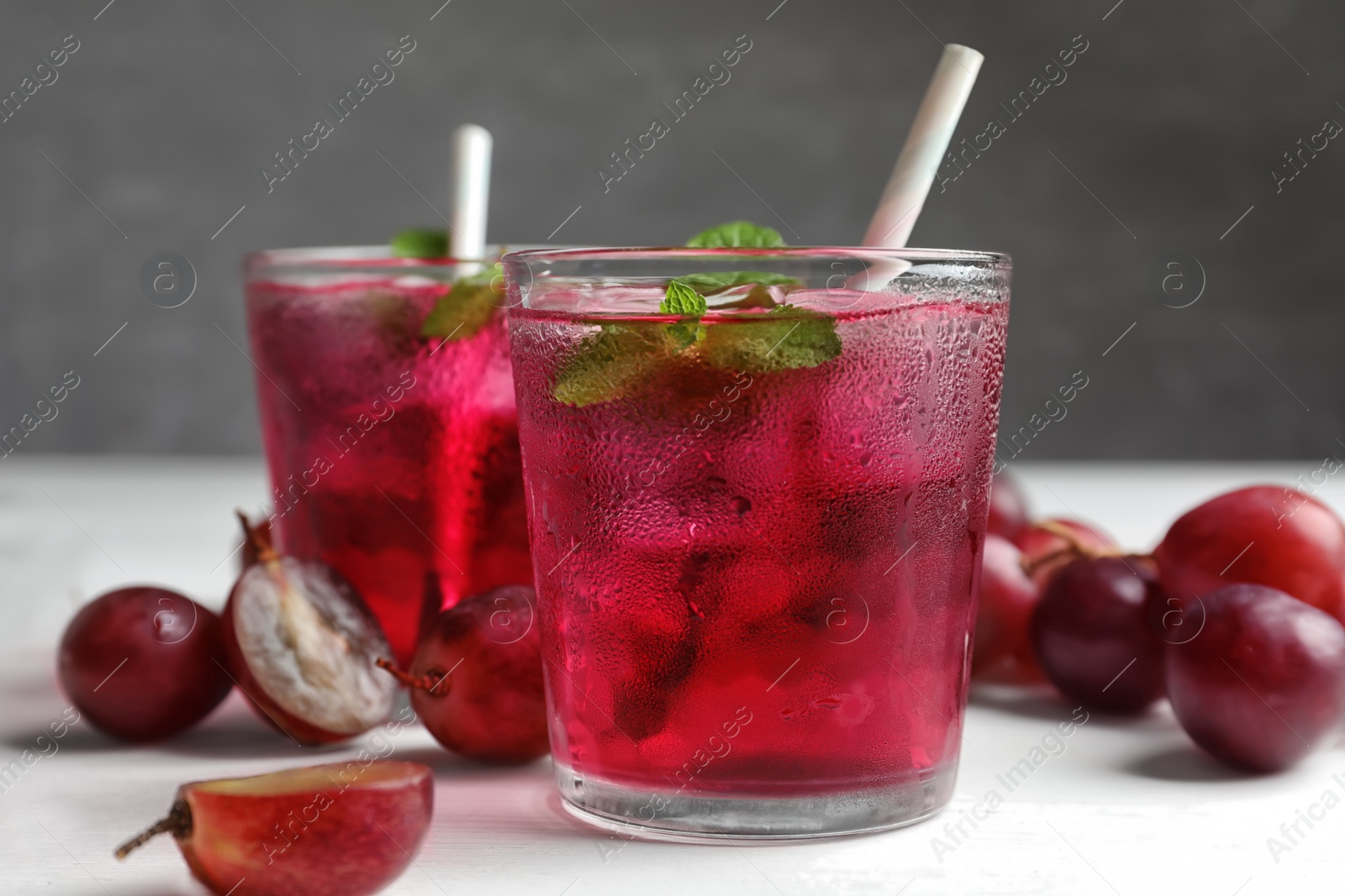 Photo of Delicious grape soda water and berries on white table. Refreshing drink