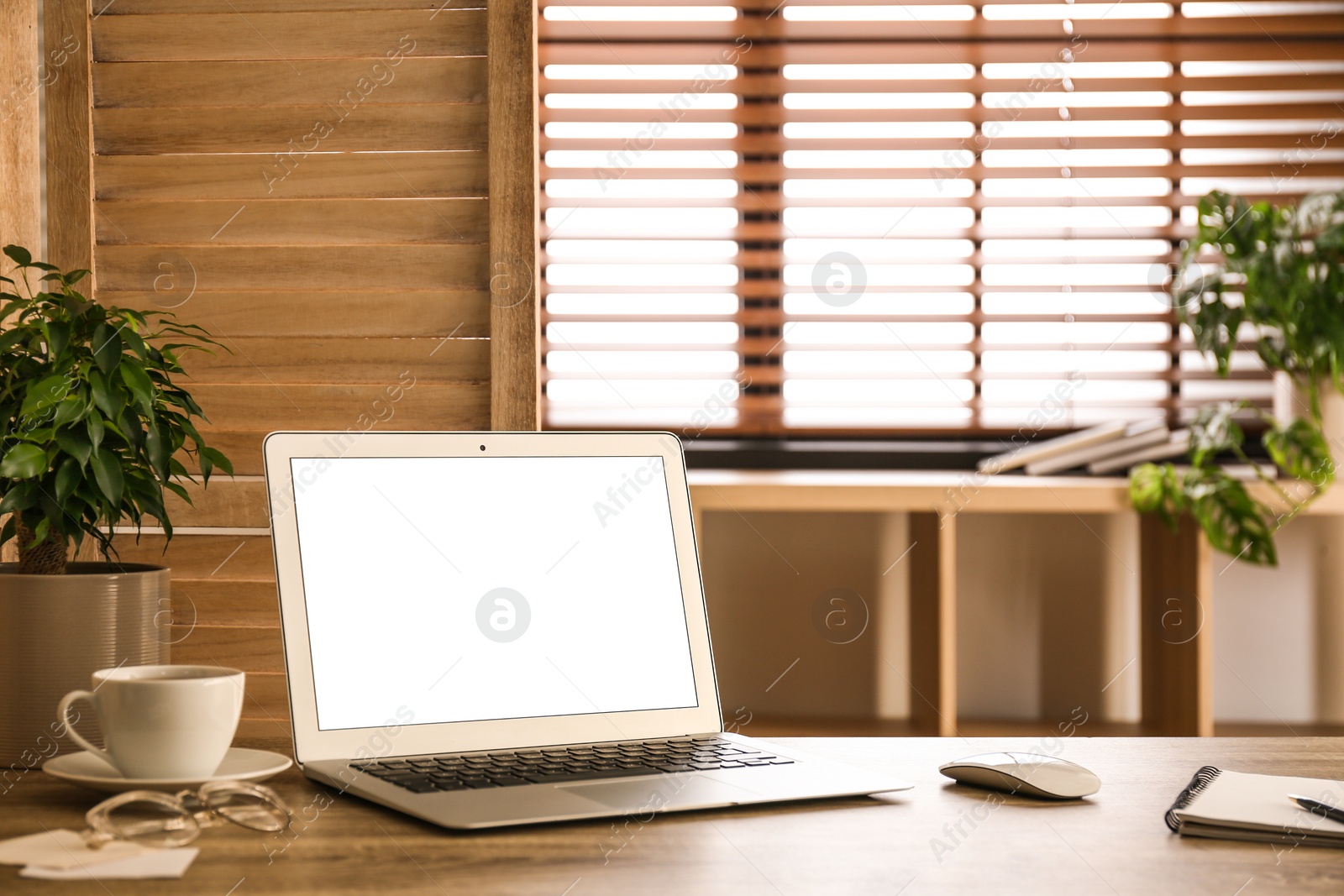 Photo of Modern laptop on table in office. Comfortable workplace