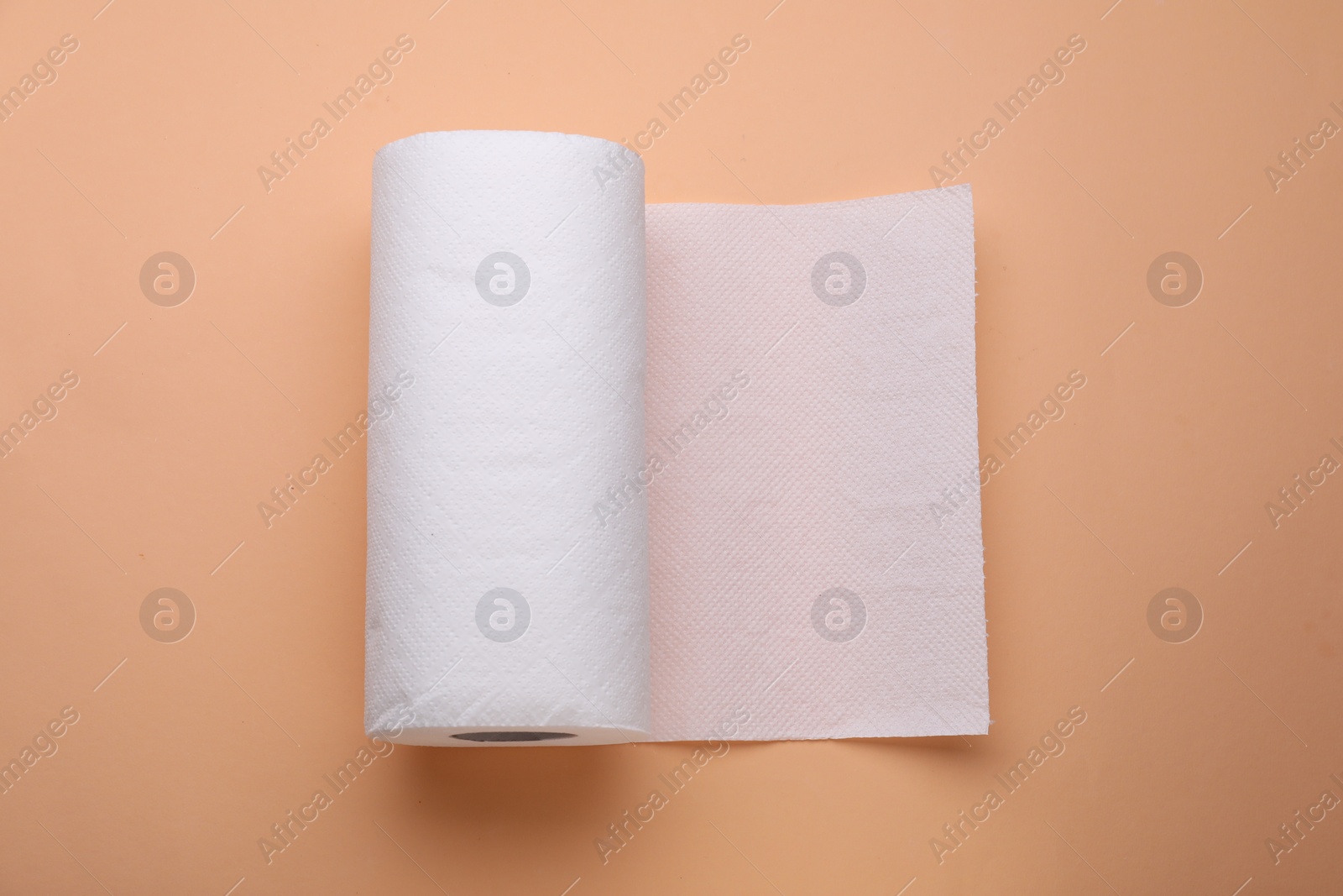 Photo of Roll of tissue towels on beige background, top view