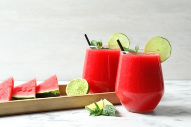 Photo of Summer watermelon drink in glasses and sliced fruits on table