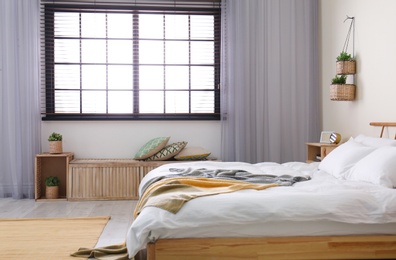 Photo of Modern room interior with comfortable double bed and window blinds