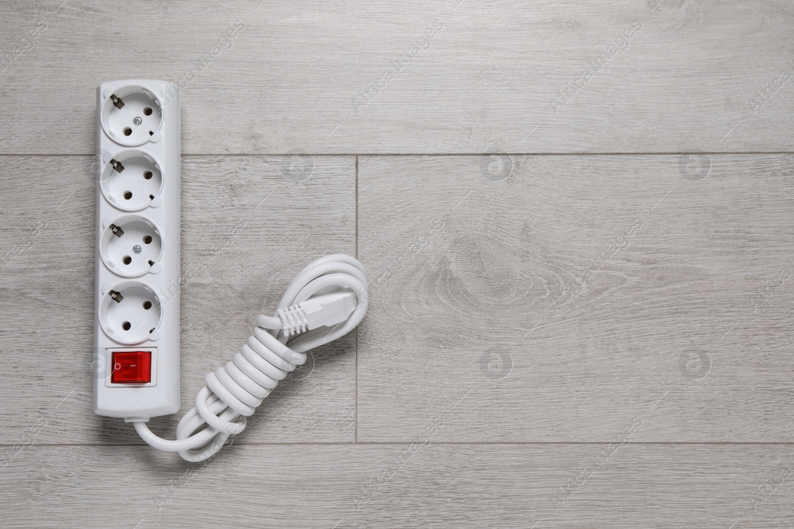 Photo of Power strip on wooden floor, top view. Space for text