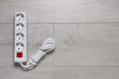 Photo of Power strip on wooden floor, top view. Space for text