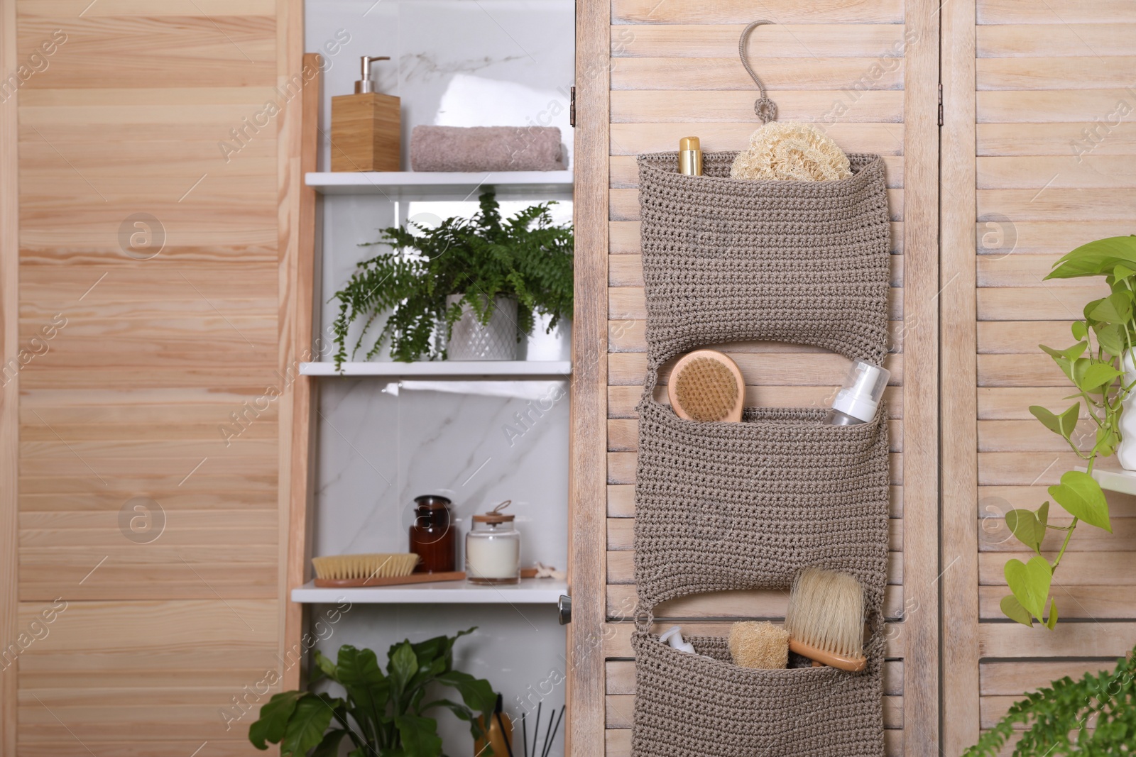 Photo of Shelving unit and organizer with essentials in bathroom. Stylish accessory