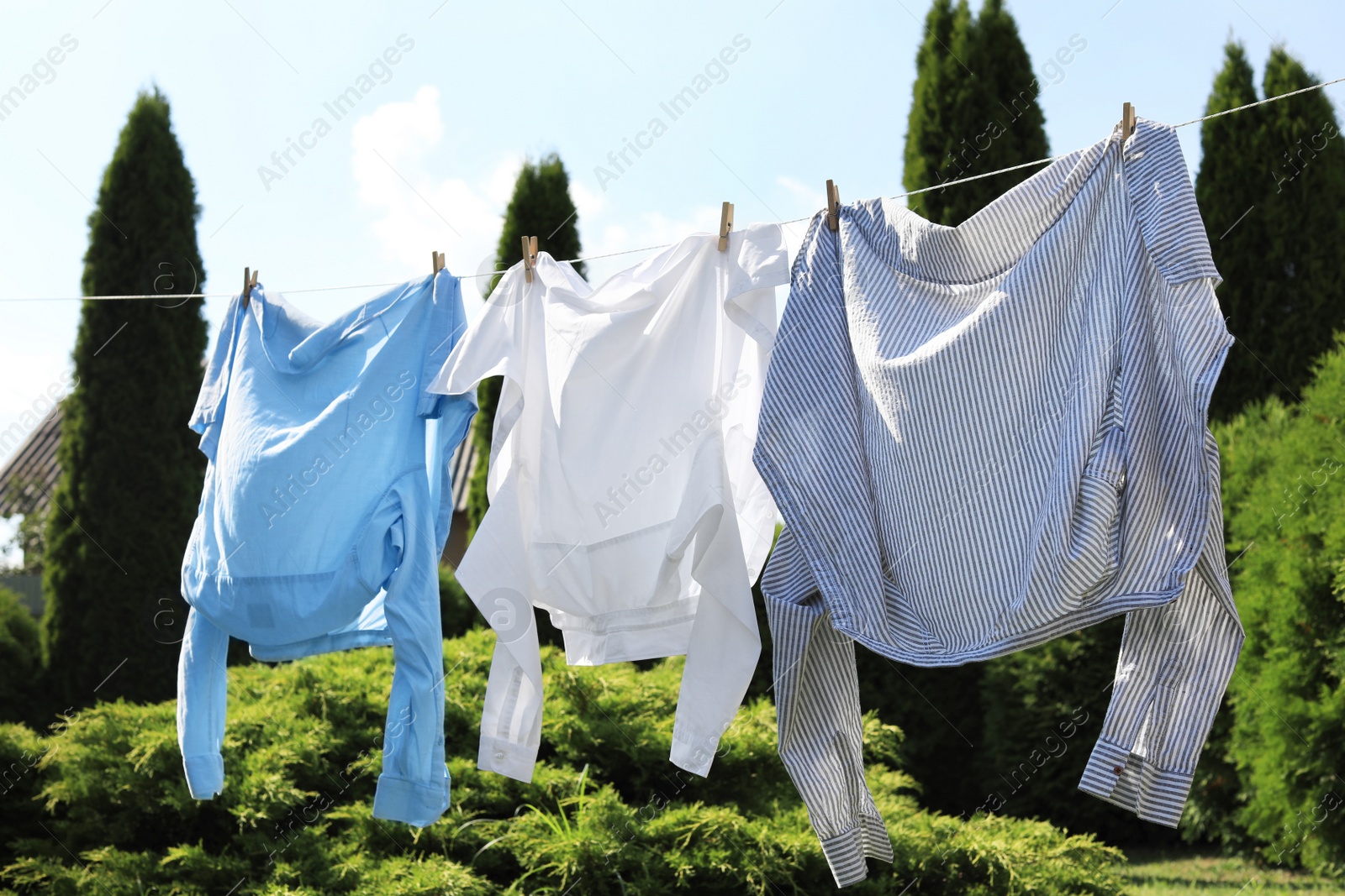 Photo of Clean clothes hanging on washing line in garden. Drying laundry