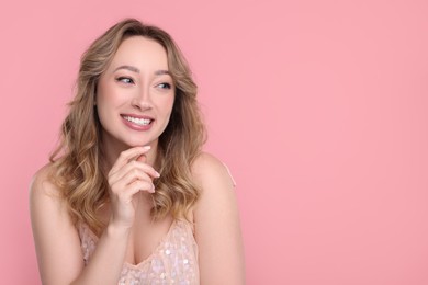 Photo of Portrait of smiling woman on pink background. Space for text
