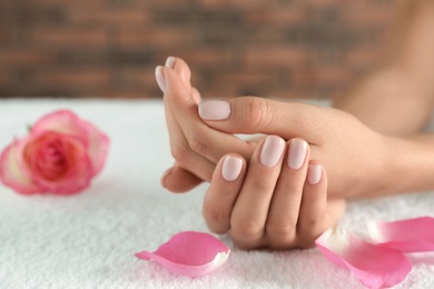 Photo of Closeup of woman with smooth hands and flower petals on towel, space for text. Spa treatment