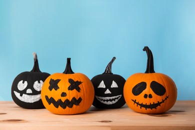 Photo of Halloween celebration. Pumpkins with spooky drawn faces on wooden table, space for text