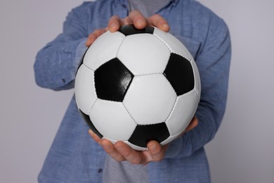 Photo of Athletic man with soccer ball on light grey background, closeup